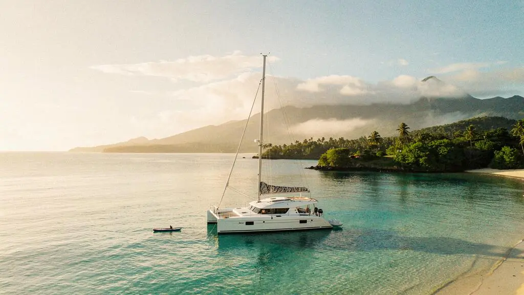 Catamaran ancré dans une baie turquoise au lever du soleil, symbole d'un nouveau rapport au voyage