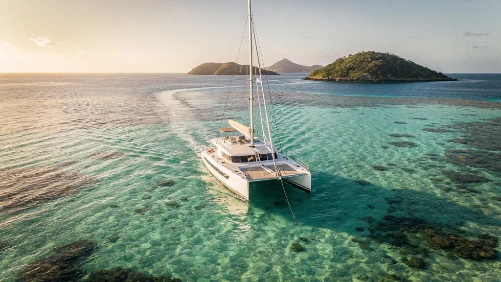 Catamaran de voyage ancré au-dessus d'un plateau corallien turquoise dans les Antilles, vue aérienne