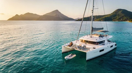 Catamaran de luxe avec équipage ancré dans une baie paradisiaque au coucher du soleil, illustrant des vacances haut de gamme