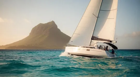 Voilier monocoque toutes voiles dehors gîtant légèrement sur une mer turquoise des Caraïbes au coucher du soleil