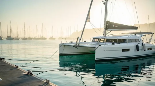 Catamaran de voyage amarré dans une marina au lever du soleil, symbole d'une réservation sereine et anticipée