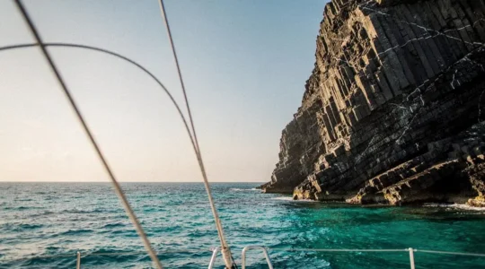 Le Rocher du Diamant vu depuis le pont d'un voilier au lever du soleil, silhouette basaltique se détachant sur la mer des Caraïbes